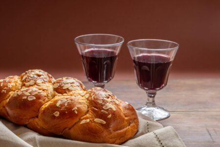 Shabbat concept, challah bread with two glasses of red wine on wooden table